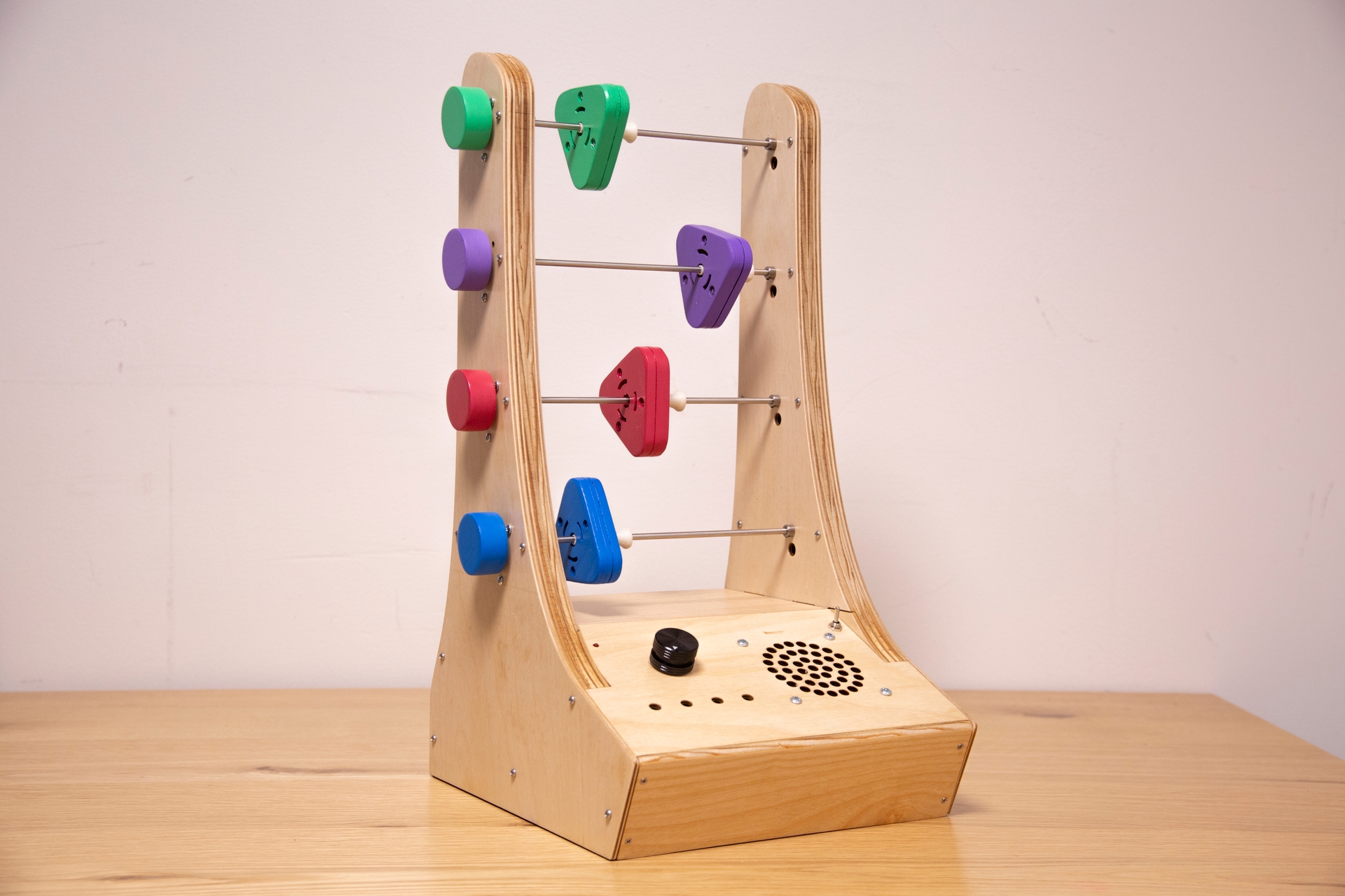 Front view of Abacusynth: a wooden device holding four rods vertically. Each rod has a colored triangular object that can spin and be moved side to side